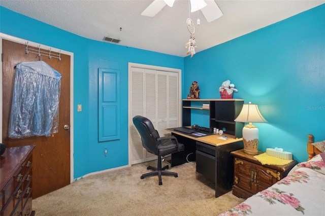 carpeted home office with a textured ceiling and ceiling fan