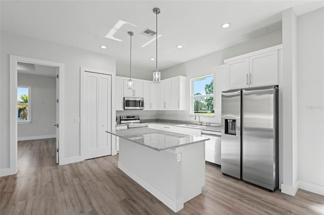 kitchen featuring sink, white cabinetry, a center island, stainless steel appliances, and light stone countertops