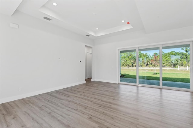 spare room featuring a raised ceiling and light hardwood / wood-style floors