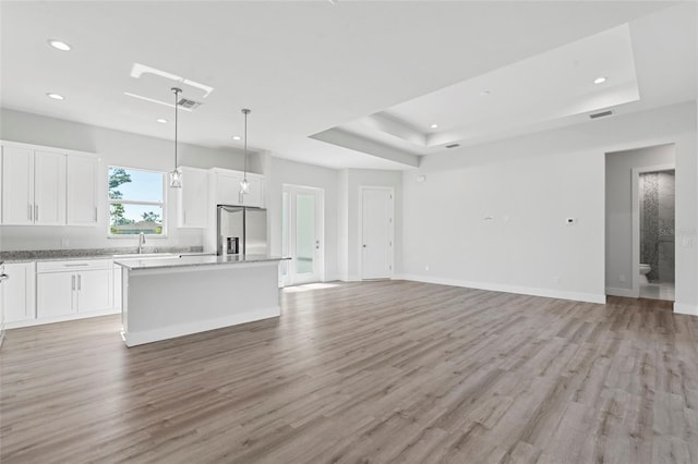 kitchen with white cabinetry, stainless steel fridge with ice dispenser, a center island, and a raised ceiling