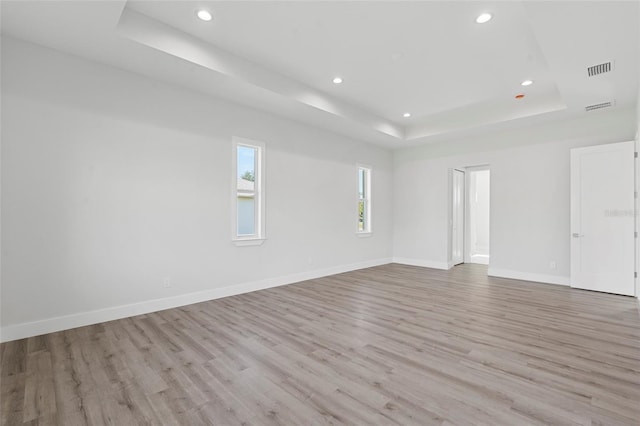 unfurnished room featuring light hardwood / wood-style flooring and a raised ceiling