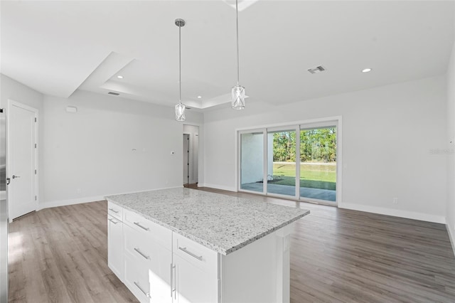 kitchen featuring white cabinetry, hanging light fixtures, light hardwood / wood-style floors, a tray ceiling, and light stone countertops