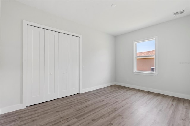 unfurnished bedroom with a closet and light wood-type flooring