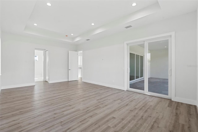 spare room with a raised ceiling and light wood-type flooring