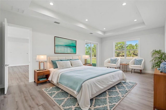 bedroom featuring light wood-type flooring and a tray ceiling