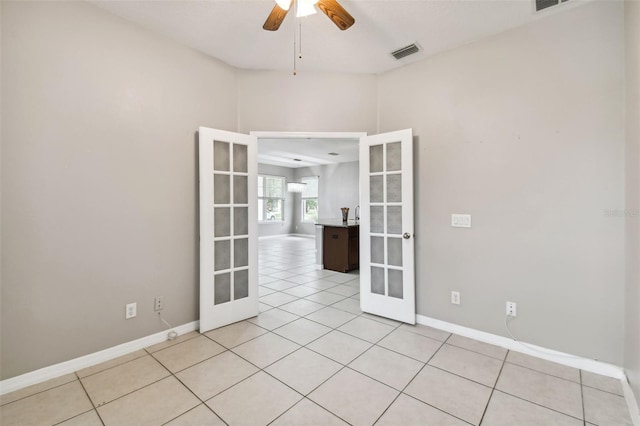 tiled empty room featuring french doors and ceiling fan