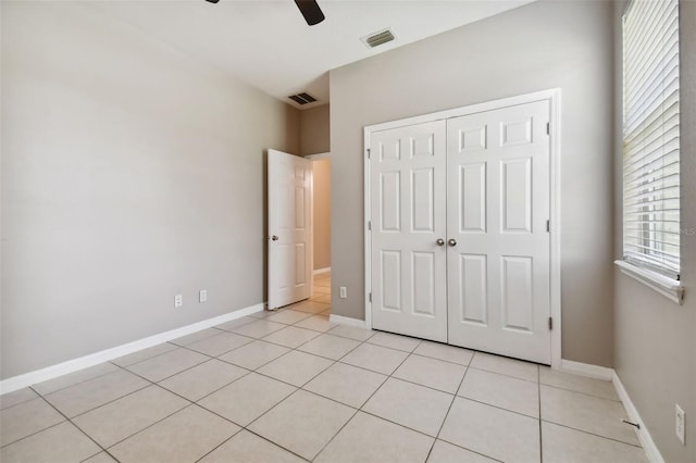 unfurnished bedroom with light tile patterned floors, a closet, and ceiling fan