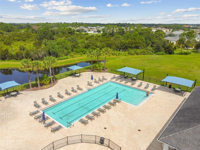 view of swimming pool featuring a patio, a water view, and a lawn