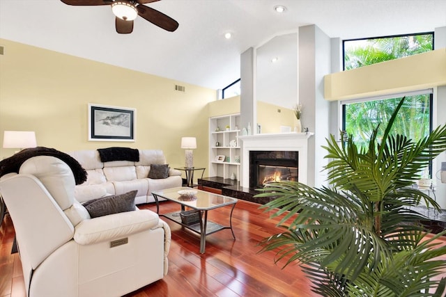 living room featuring hardwood / wood-style floors, a fireplace, high vaulted ceiling, and ceiling fan