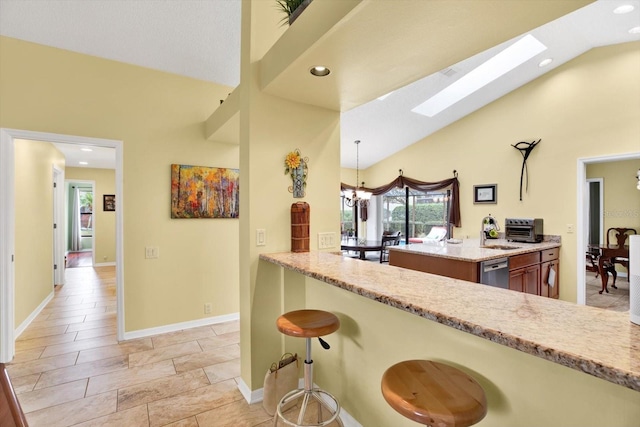 kitchen featuring a kitchen bar, decorative light fixtures, a skylight, dishwasher, and kitchen peninsula