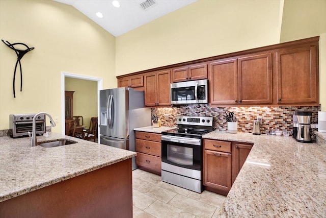 kitchen featuring sink, light stone counters, tasteful backsplash, high vaulted ceiling, and stainless steel appliances