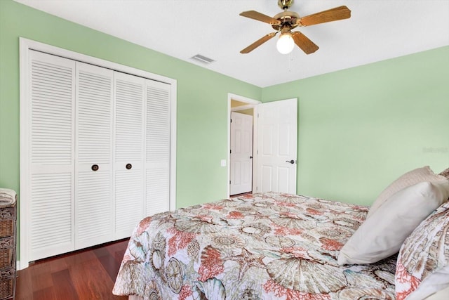 bedroom with dark wood-type flooring, ceiling fan, and a closet