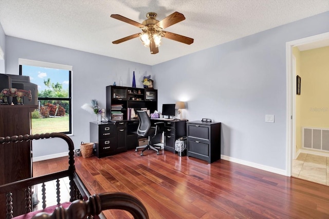 office space with ceiling fan, dark wood-type flooring, and a textured ceiling