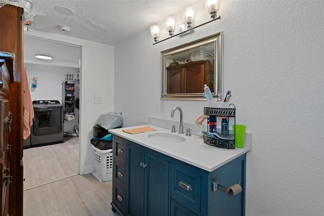 bathroom with hardwood / wood-style flooring, vanity, washer / dryer, and a textured ceiling