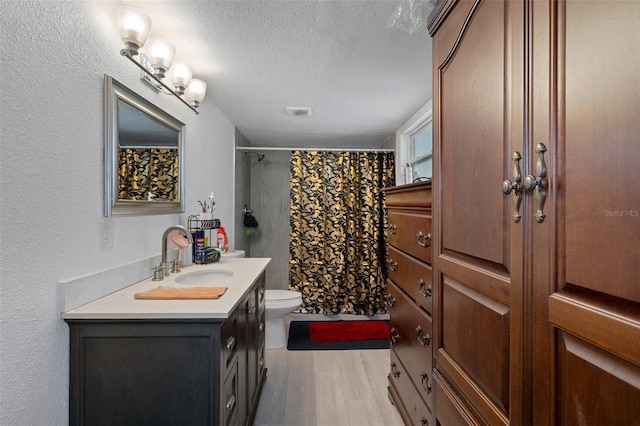 bathroom with toilet, wood-type flooring, a textured ceiling, vanity, and curtained shower