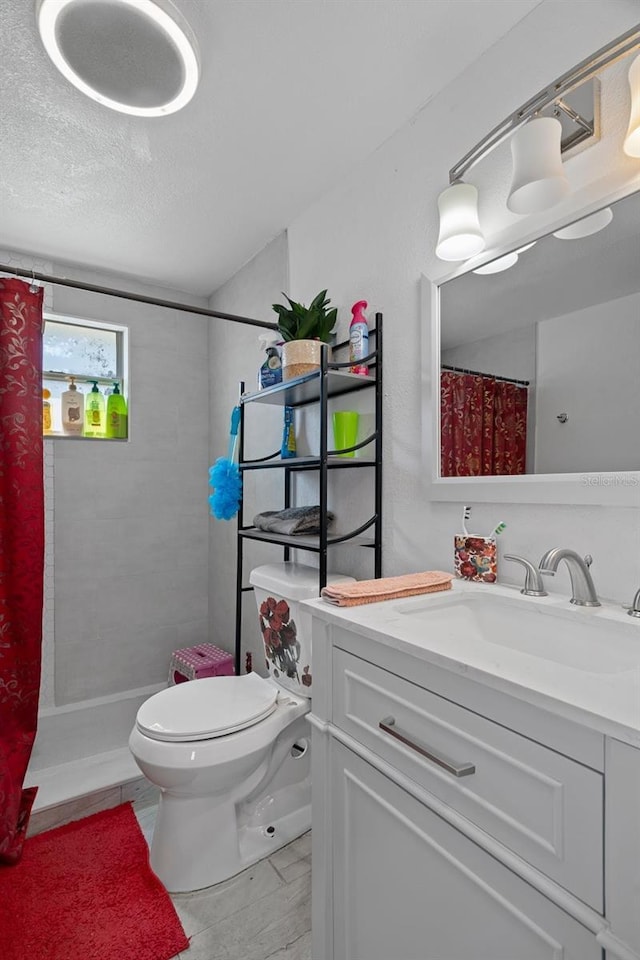 bathroom with vanity, walk in shower, a textured ceiling, and toilet