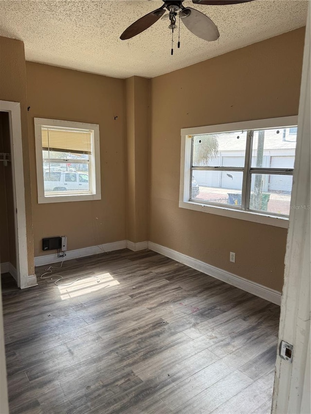 unfurnished bedroom with multiple windows, wood finished floors, and baseboards