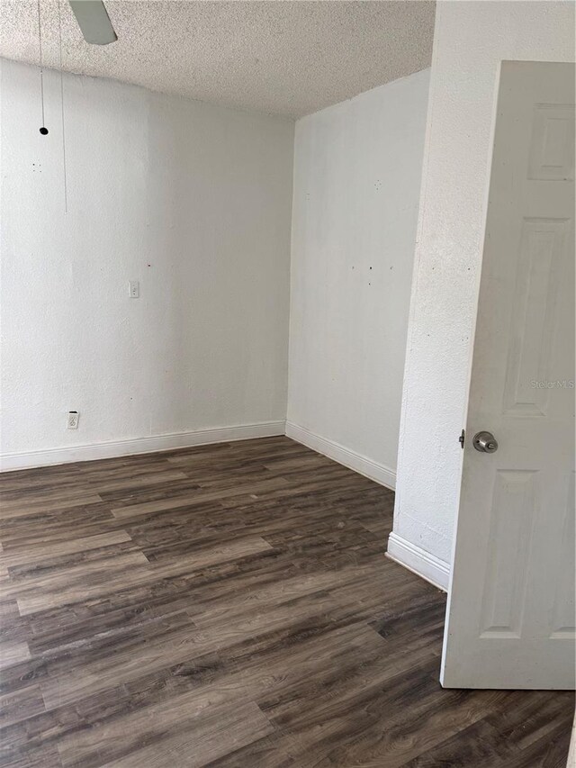 spare room with dark wood-style floors, a textured ceiling, and baseboards