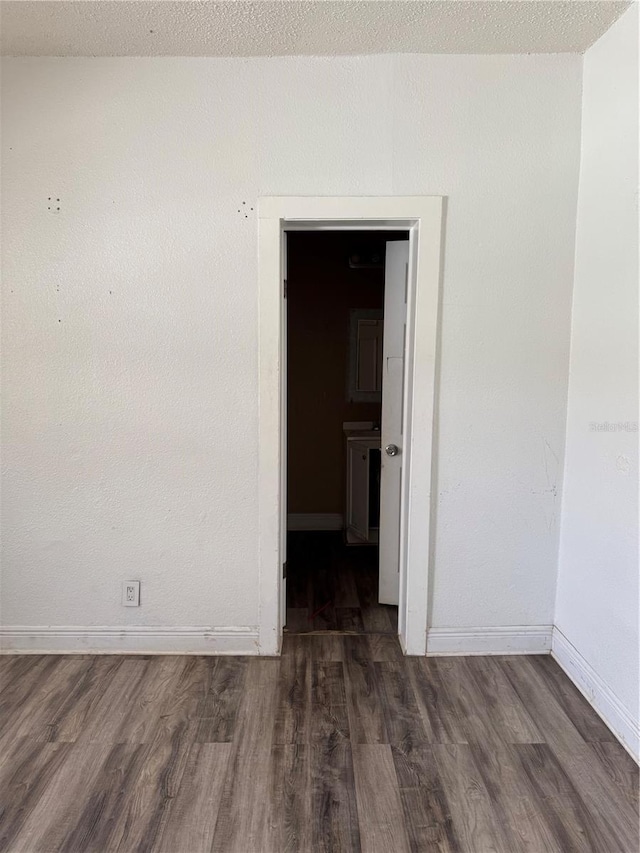 unfurnished room featuring a textured ceiling, baseboards, and dark wood-type flooring