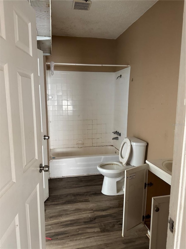 bathroom featuring a textured ceiling, toilet, wood finished floors, visible vents, and vanity