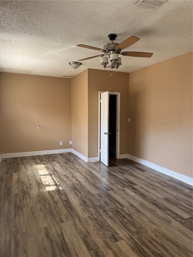 unfurnished room featuring visible vents, dark wood-type flooring, a ceiling fan, a textured ceiling, and baseboards