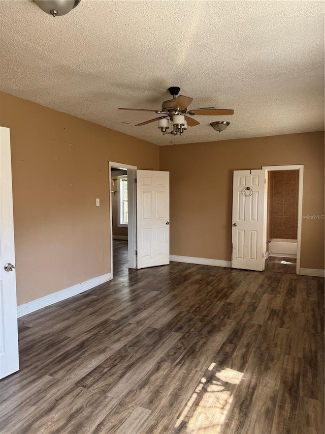 unfurnished room featuring dark wood-style floors, a textured ceiling, and baseboards