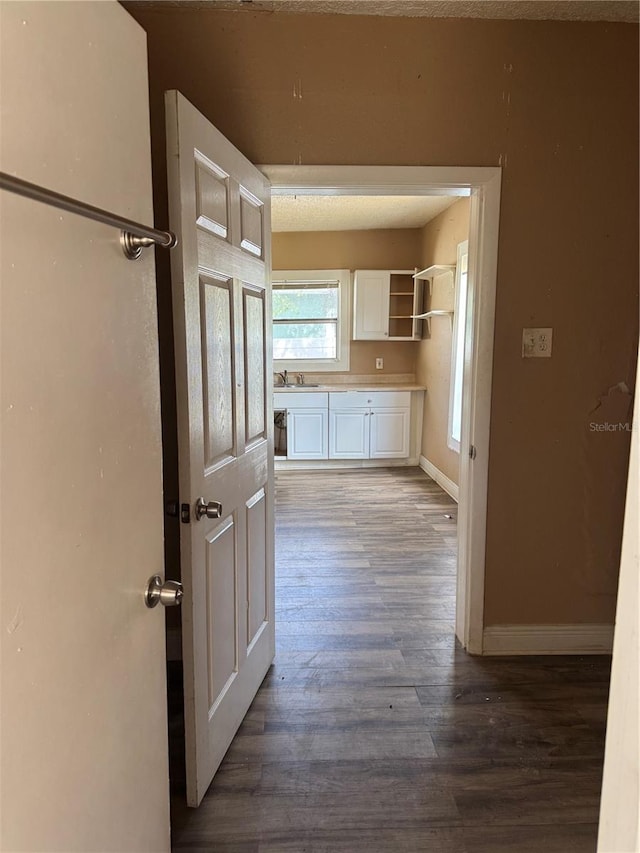 kitchen with baseboards, white cabinets, dark wood-style floors, open shelves, and a sink