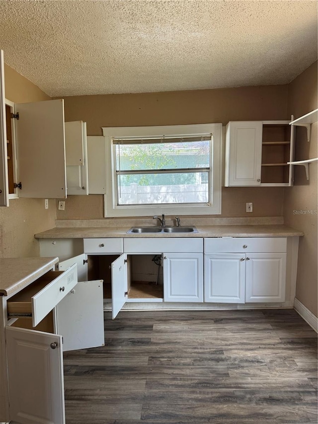 kitchen with a textured ceiling, white cabinetry, light countertops, and a sink