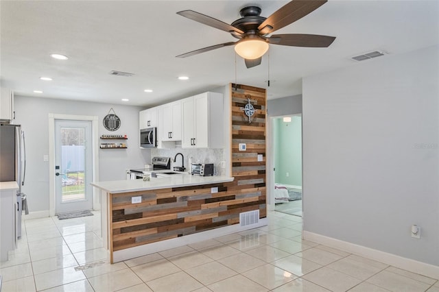 kitchen featuring white cabinetry, appliances with stainless steel finishes, light tile patterned flooring, and backsplash