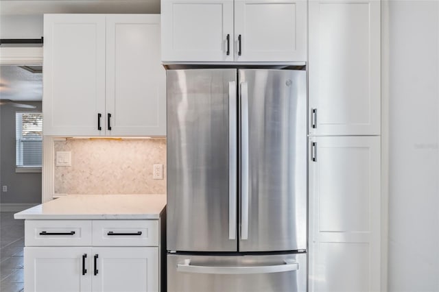 kitchen featuring white cabinetry, light stone counters, stainless steel fridge, and tasteful backsplash