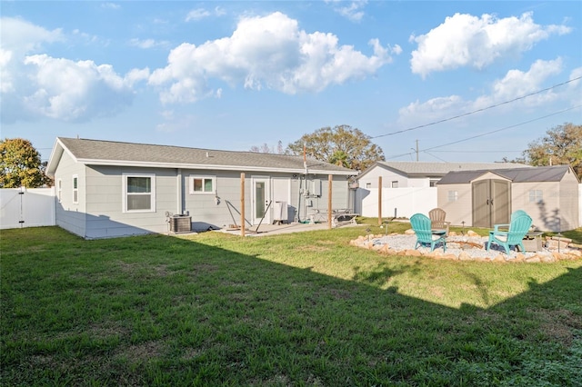 rear view of property with a storage unit, a yard, a patio area, and an outdoor fire pit