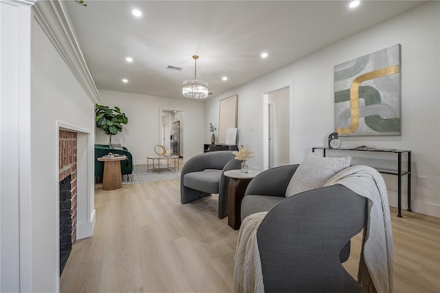 living room with an inviting chandelier, a fireplace, and light hardwood / wood-style flooring