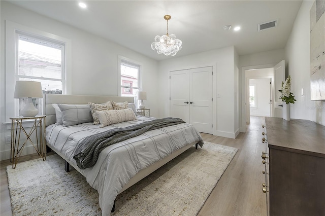 bedroom with a closet, a chandelier, and light hardwood / wood-style flooring