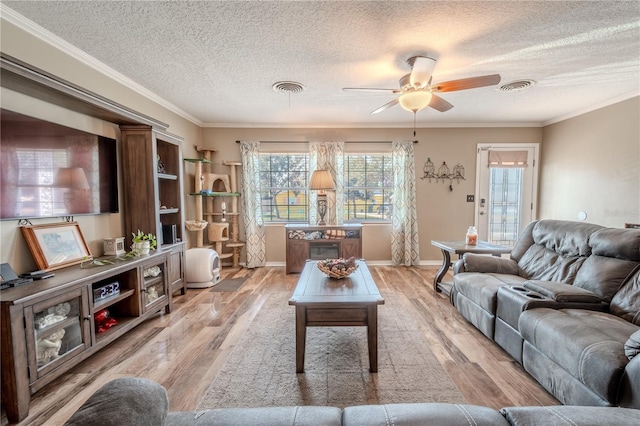 living room featuring ceiling fan, ornamental molding, a textured ceiling, and light wood-type flooring