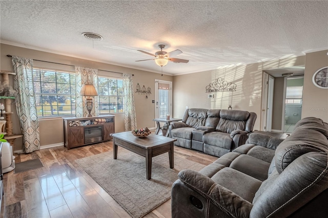 living room featuring ornamental molding, ceiling fan, a textured ceiling, and light hardwood / wood-style floors