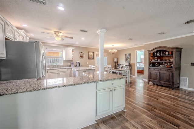 kitchen featuring stainless steel refrigerator, white cabinetry, decorative columns, dark hardwood / wood-style flooring, and kitchen peninsula