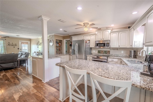 kitchen featuring appliances with stainless steel finishes, white cabinetry, sink, a kitchen breakfast bar, and kitchen peninsula