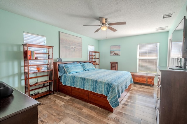 bedroom with ceiling fan, wood-type flooring, and a textured ceiling