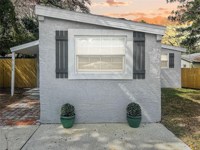 property exterior at dusk with fence and stucco siding