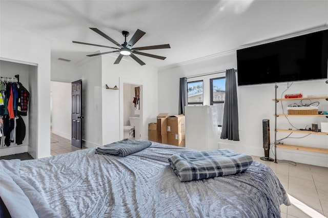 bedroom with ceiling fan, tile patterned floors, and ensuite bathroom