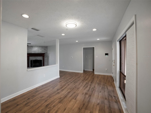 unfurnished living room featuring a fireplace, hardwood / wood-style floors, and a textured ceiling