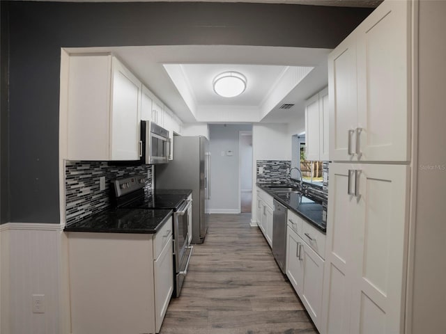 kitchen with sink, white cabinetry, hardwood / wood-style floors, stainless steel appliances, and a raised ceiling