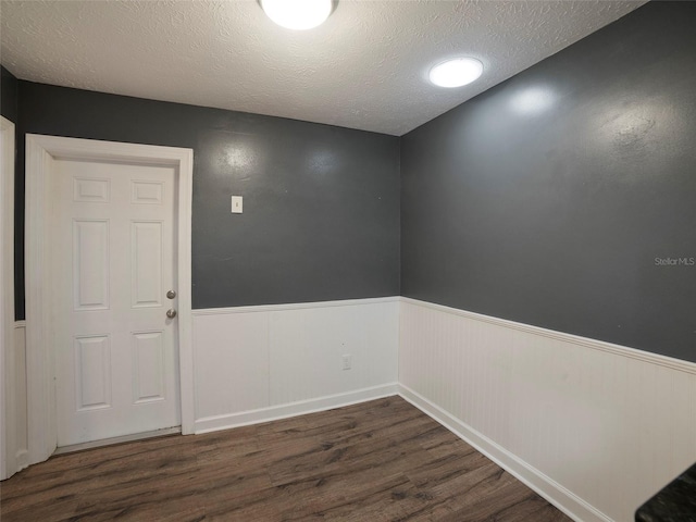 empty room with dark wood-type flooring and a textured ceiling