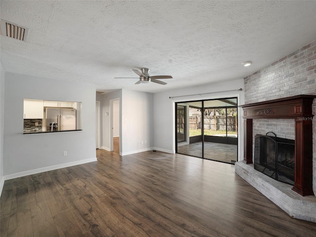 unfurnished living room featuring dark hardwood / wood-style flooring, a textured ceiling, ceiling fan, and a fireplace