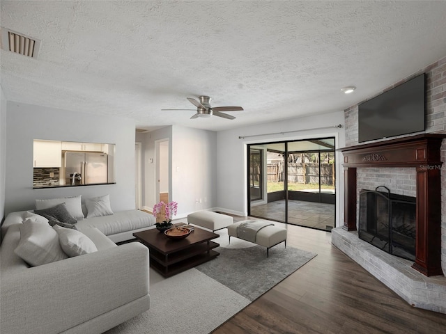 living room featuring ceiling fan, hardwood / wood-style floors, a textured ceiling, and a fireplace