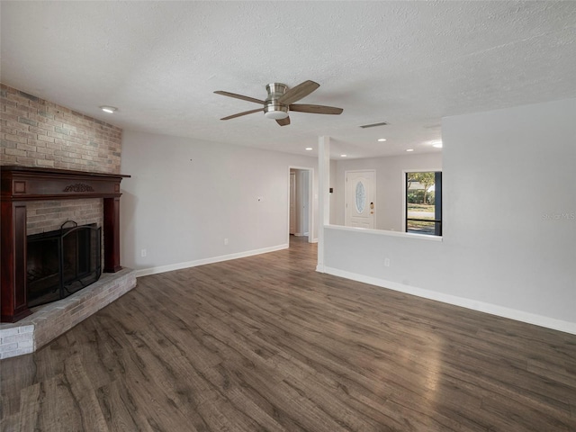 unfurnished living room with ceiling fan, a fireplace, dark hardwood / wood-style floors, and a textured ceiling