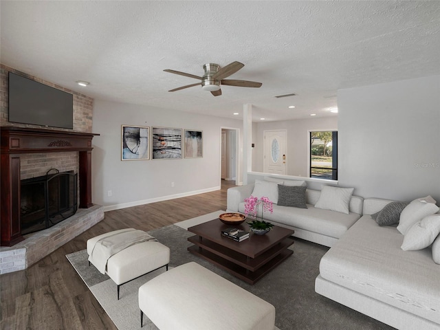 living room featuring a textured ceiling, dark hardwood / wood-style flooring, and a fireplace