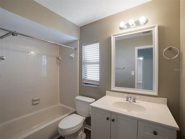 full bathroom with tiled shower / bath combo, vanity, a textured ceiling, and toilet