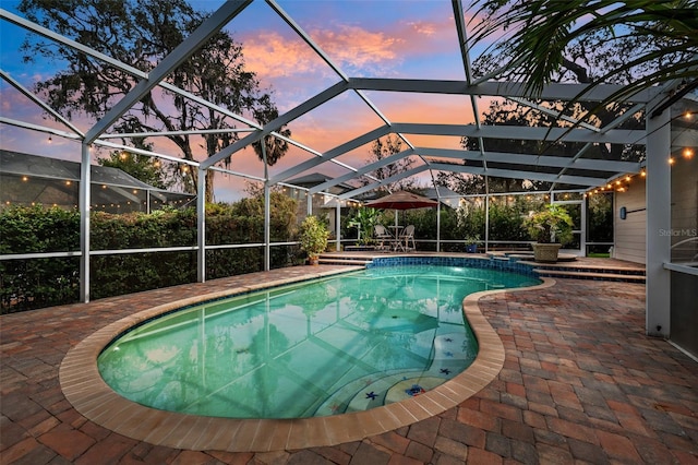 pool at dusk with a patio and glass enclosure