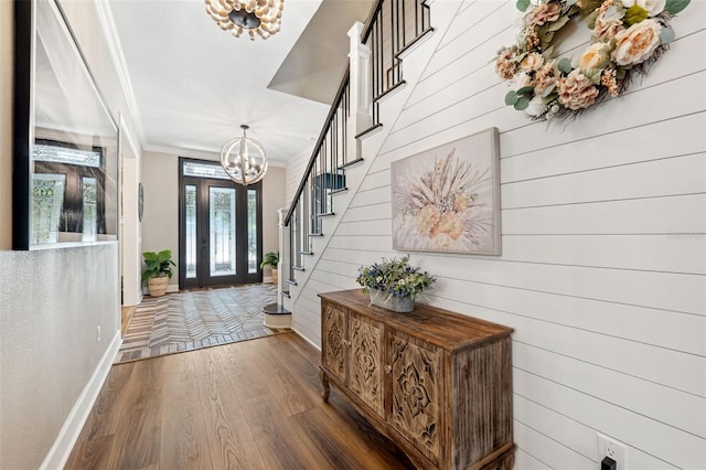 foyer entrance featuring crown molding, wooden walls, dark hardwood / wood-style flooring, and a notable chandelier